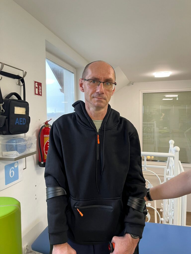 Wojciech Niedźwiedź wsparty o kulach pozuje do zdjęcia w sali do rehabilitacji.