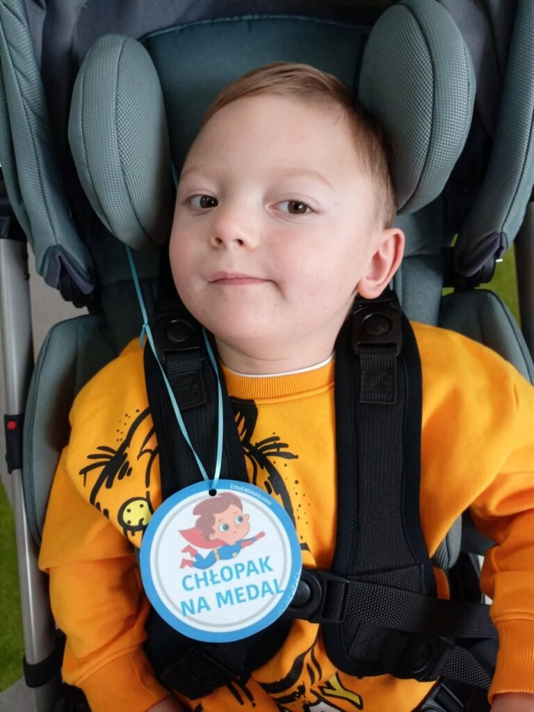 Fabian Chwedoruk uśmiechnięty patrzy w obiektyw. Na szyi ma order z napisem "chłopak na medal".