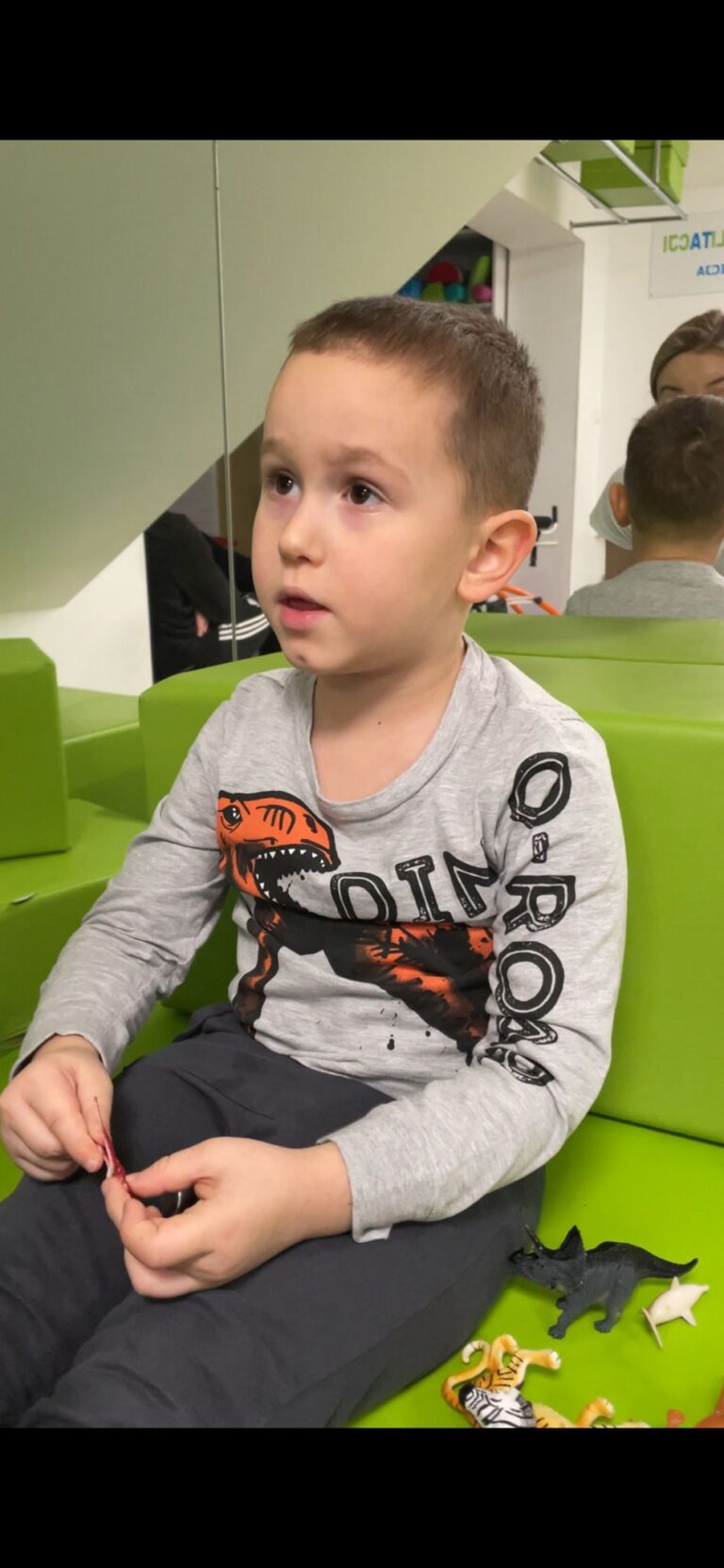 Adam Gajda bawi się figurkami dinozaurów w poczekalni.