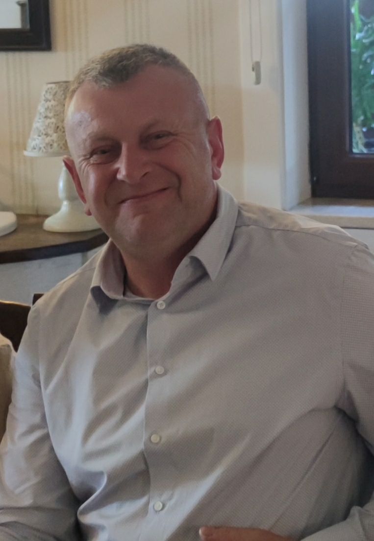 Artur Mrozek siedzi w fotelu w domowym wnętrzu i uśmiecha się.