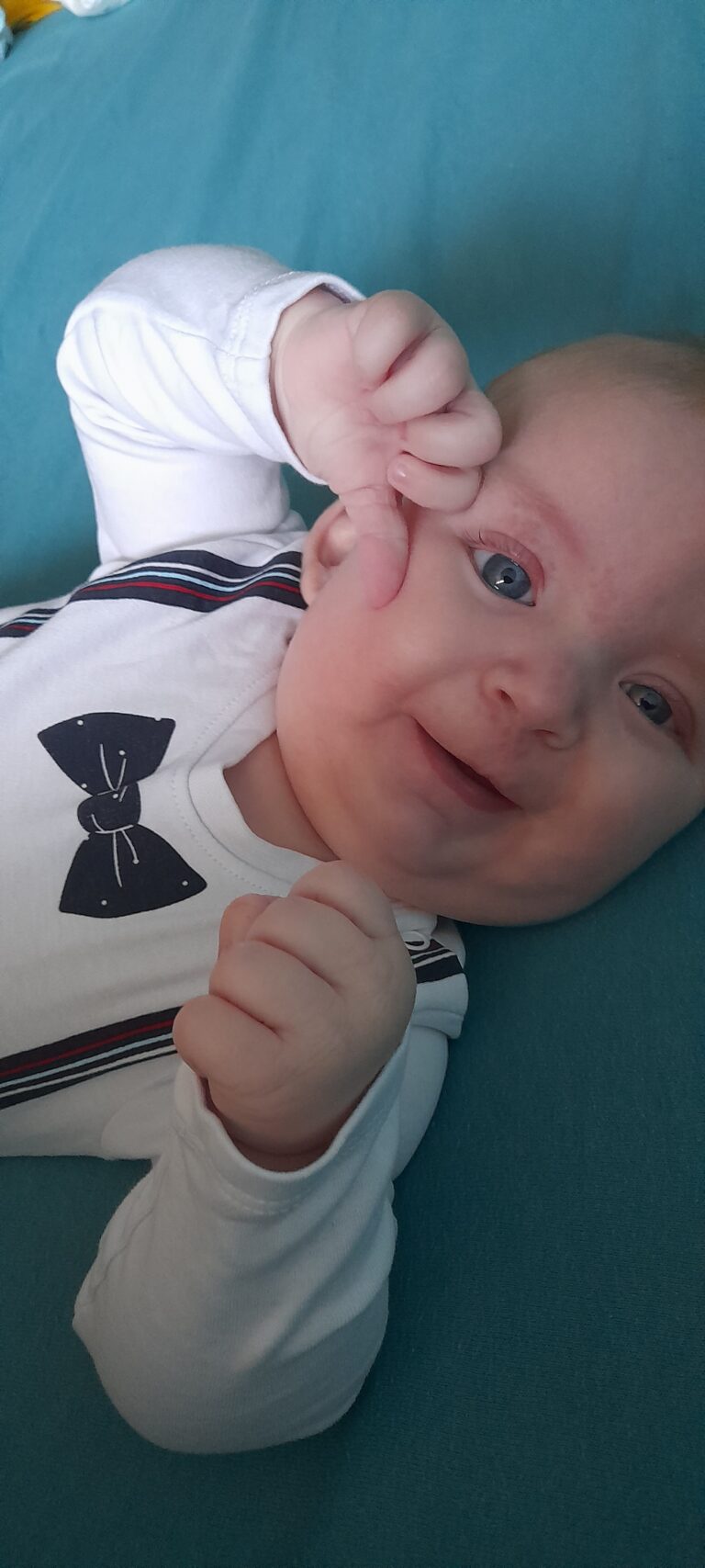 Igor Floreskul leży na kocu, uśmiecha się i podnosi rączkę do twarzy.