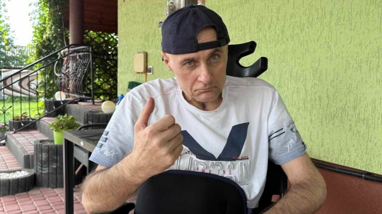 Jacek Leśniowski siedzi na tarasie i pokazuje uniesiony kciuk.