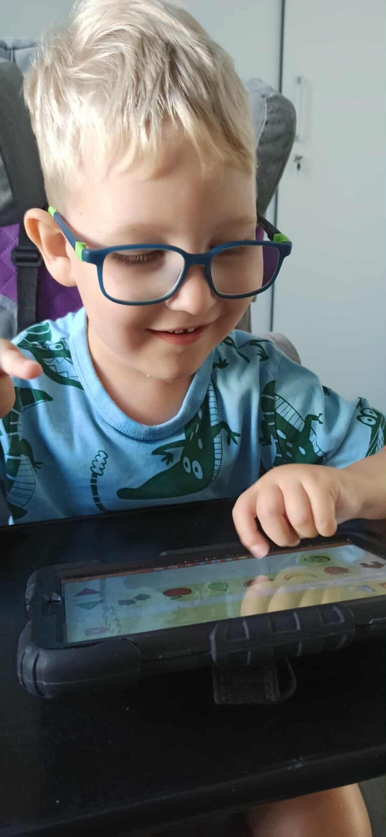Juliusz Łukasik dotyka palcem ekranu tabletu, na którym wyświetla się gra.