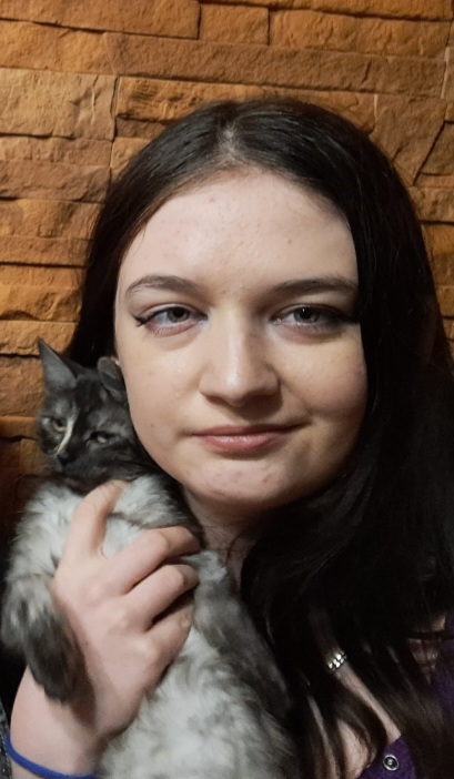 Justyna Kozieł trzyma na rękach kota i przytula go do policzka.