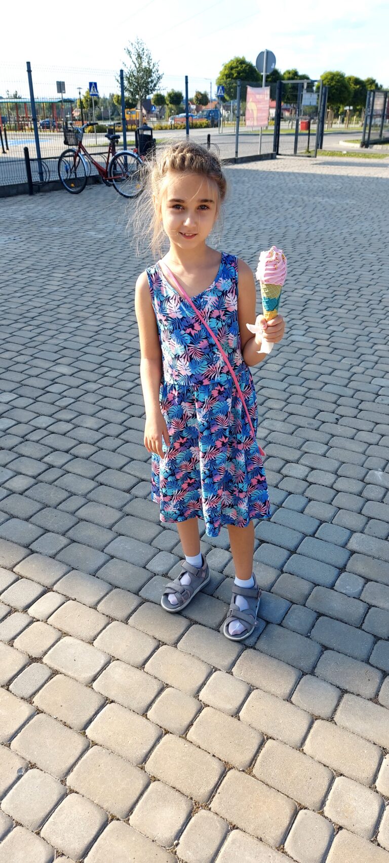 Laura Chyrza trzyma lody w wafelku na brukowanym placu.