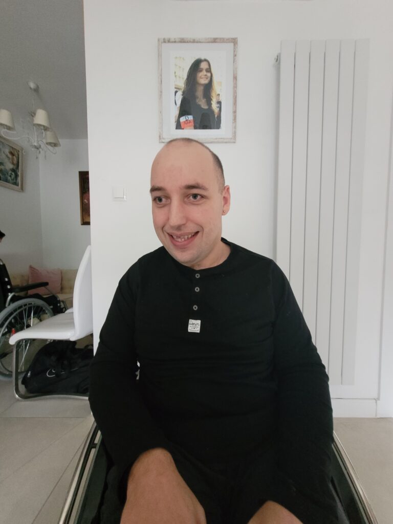 Mateusz Drwal uśmiecha się, ujęty w bliskim kadrze.
