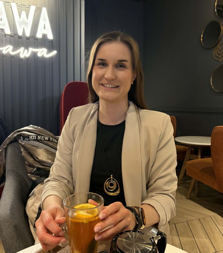 Paulina Kawecka siedzi w kawiarni i trzyma szklankę herbaty z cytryną.