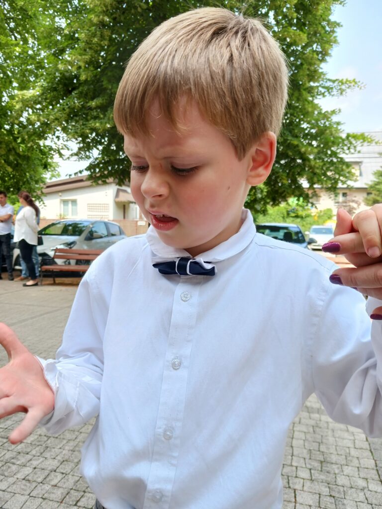 Wojciech Soszka stoi na chodniku z podniesionymi dłońmi i patrzy w dół.