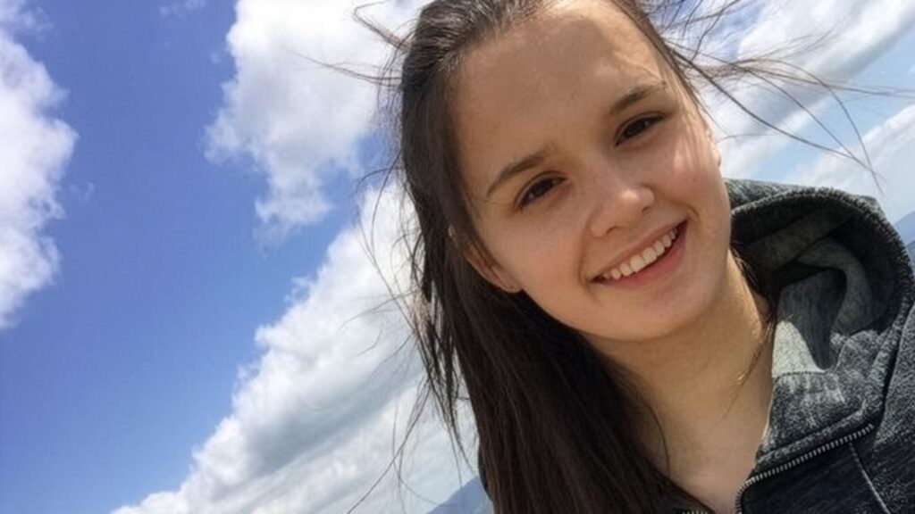 Alicja Mazurek uśmiechnięta i z rozwianymi włosami pozuje do zdjęcia na tle nieba.