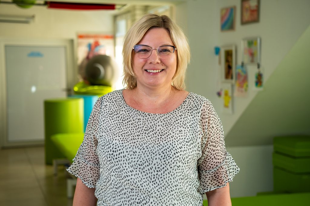 Magdalena Dobrzyńska uśmiechnięta pozuje do zdjęcia w ośrodku neurorehablitacji.