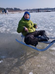 Szymon na sankach na zamarzniętej plaży
